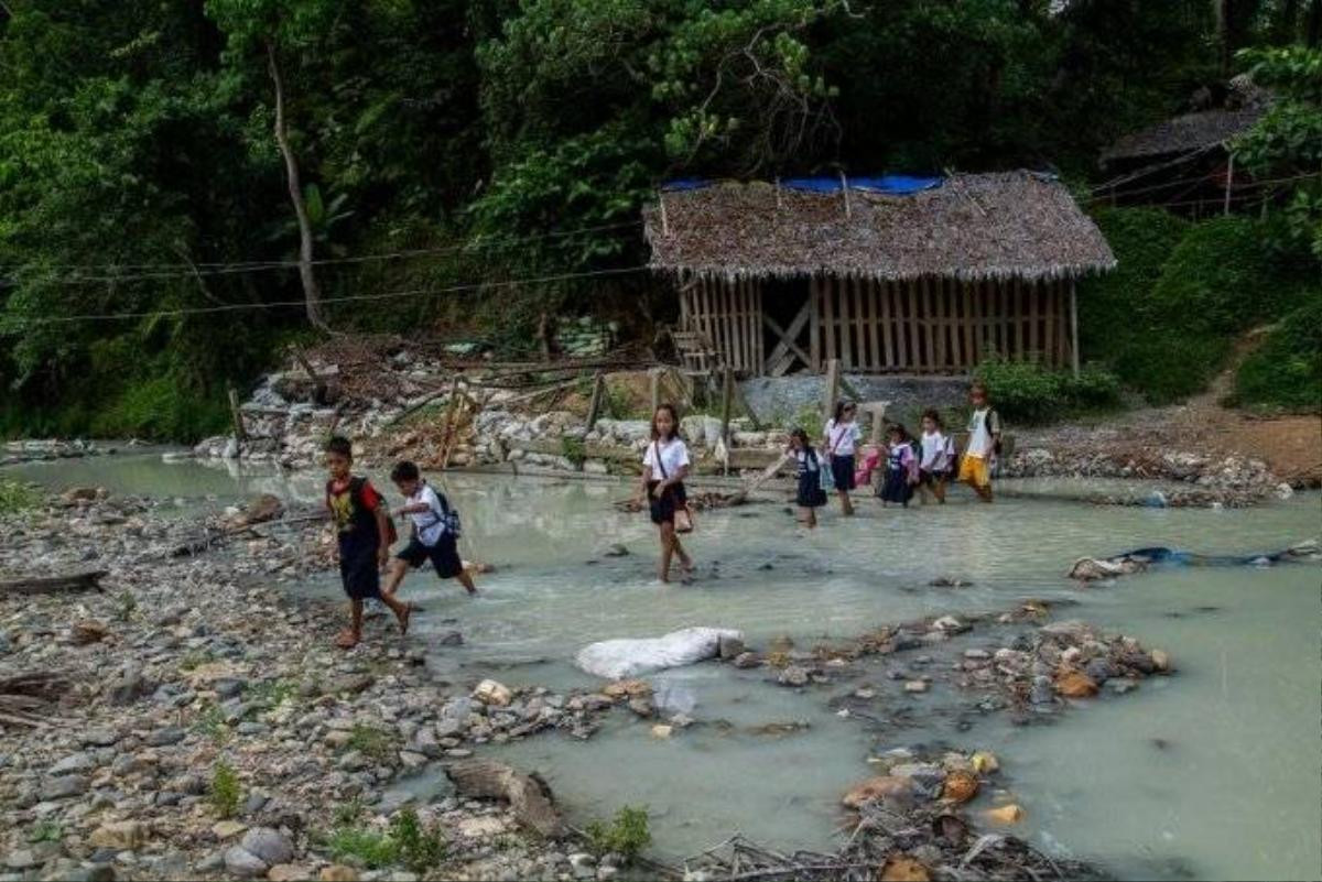 Các em nhỏ lội qua dòng sông trắng xóa do thủy ngân tan vào trong nước.