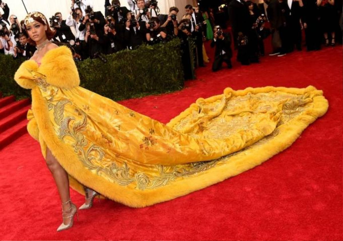 Và bộ đồ gây sốt nhất thời gian vừa qua là đây. Có mặt trên thảm đỏ chương trình Met Gala 2015, Rihanna khiến tất cả mọi người phải xuýt xoa, choáng váng với diện mạo sang trọng của nữ ca sĩ trong chiếc áo cape lông vàng rực, nặng tới 25 kg, phần đuôi dài lê thê được in các họa 