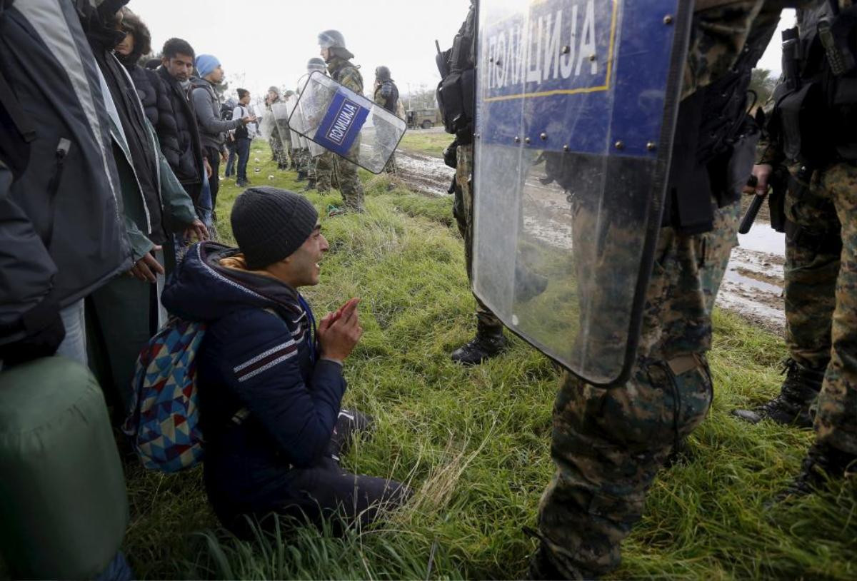 A Moroccan migrant begs Macedonian police officers to let him cross the Greek-Macedonian border near the Greek village of Idomeni November 26, 2015. Hundreds of Moroccans, Algerians and Pakistanis tried to storm the border between Greece and Macedonia on Thursday, tearing down part of the barbed wire fence at the crossing and demanding to be allowed to carry on into northern Europe. REUTERS/Yannis Behrakis