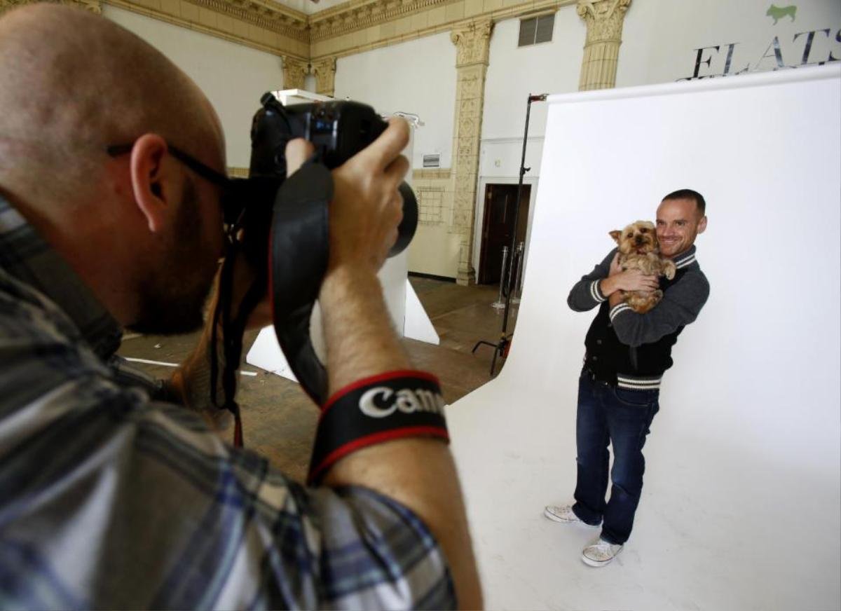 In this photo taken on Saturday, Nov. 14, 2015, photographer Jesse Freidin shoots portraits of Dr. Robert Garofalo and his dog, Fred, in Chicago. Garofalo, who is head of the adolescent medicine division at Lurie Children's Hospital of Chicago, tested positive for the AIDS virus in 2010. He fell into a deep depression and credits Fred, a Yorkshire terrier, with bringing him back to life. Garofalo has since co-founded the "When Dogs Heal" photo project, which features Freidin's portraits of HIV-positive people and their dogs. The exhibit opens in Chicago on Dec. 1, which is World AIDS Day, and in New York City on Dec. 3. (AP Photo/Martha Irvine)