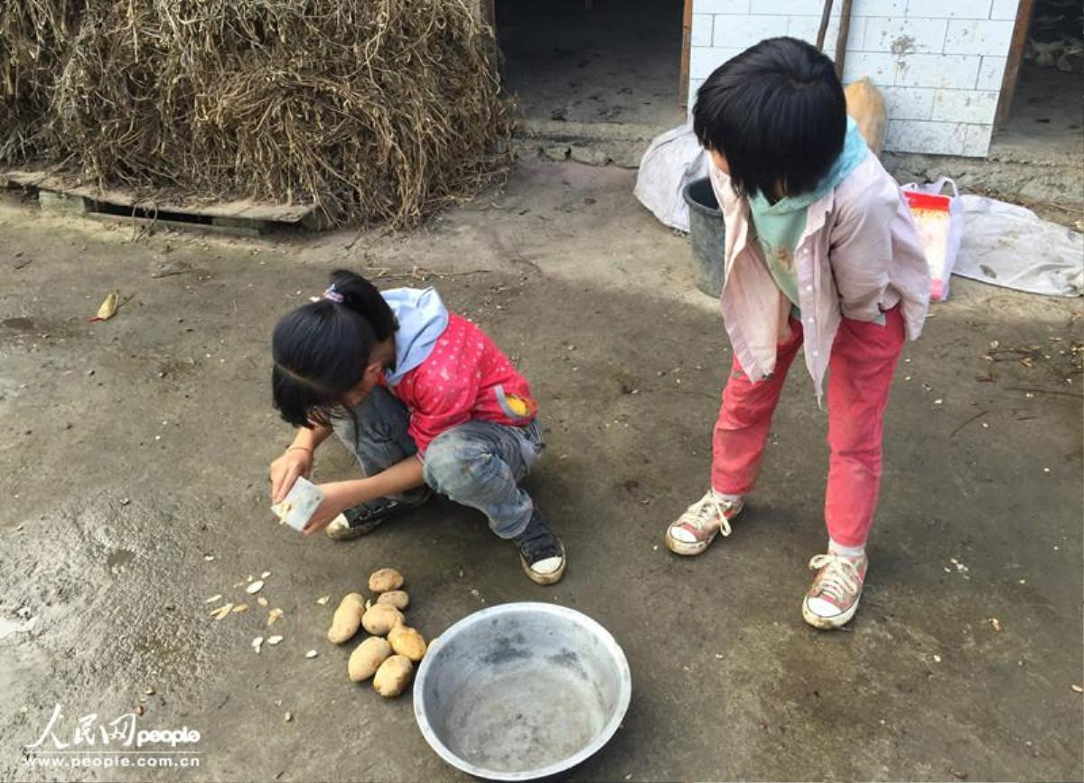 Hai chị em cô bé này đang gọt khoai nấu bữa tối. Các em hiện đang sống tại làng Baihua, tỉnh Quý Châu. Mẹ em đã chết vì bạo bệnh, còn cha thì lên thành phố kiếm tiền. Chỉ có hai chị em nương tựa vào nhau mà sống.