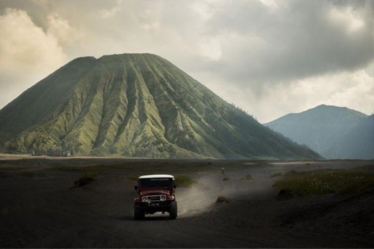 Chiếc ôtô chở khách đi trên nền tro bụi núi lửa, với phông nền là ngọn núi Bromo hùng vĩ có thể khiến bất cứ ai có tinh thần phiêu lưu muốn xách balô lên và đi.