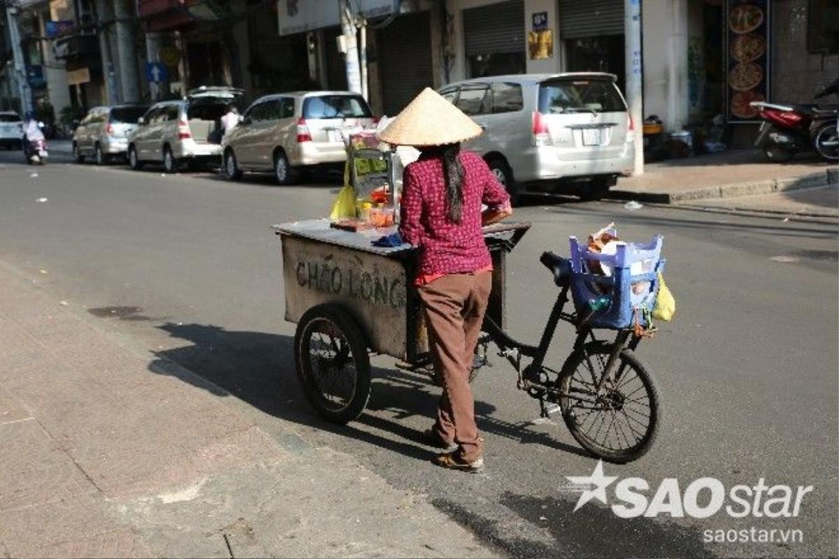 Chị bán cháo lòng đạp xe qua được mọi người gọi vào chỉ cho thấy tủ bánh từ thiện.