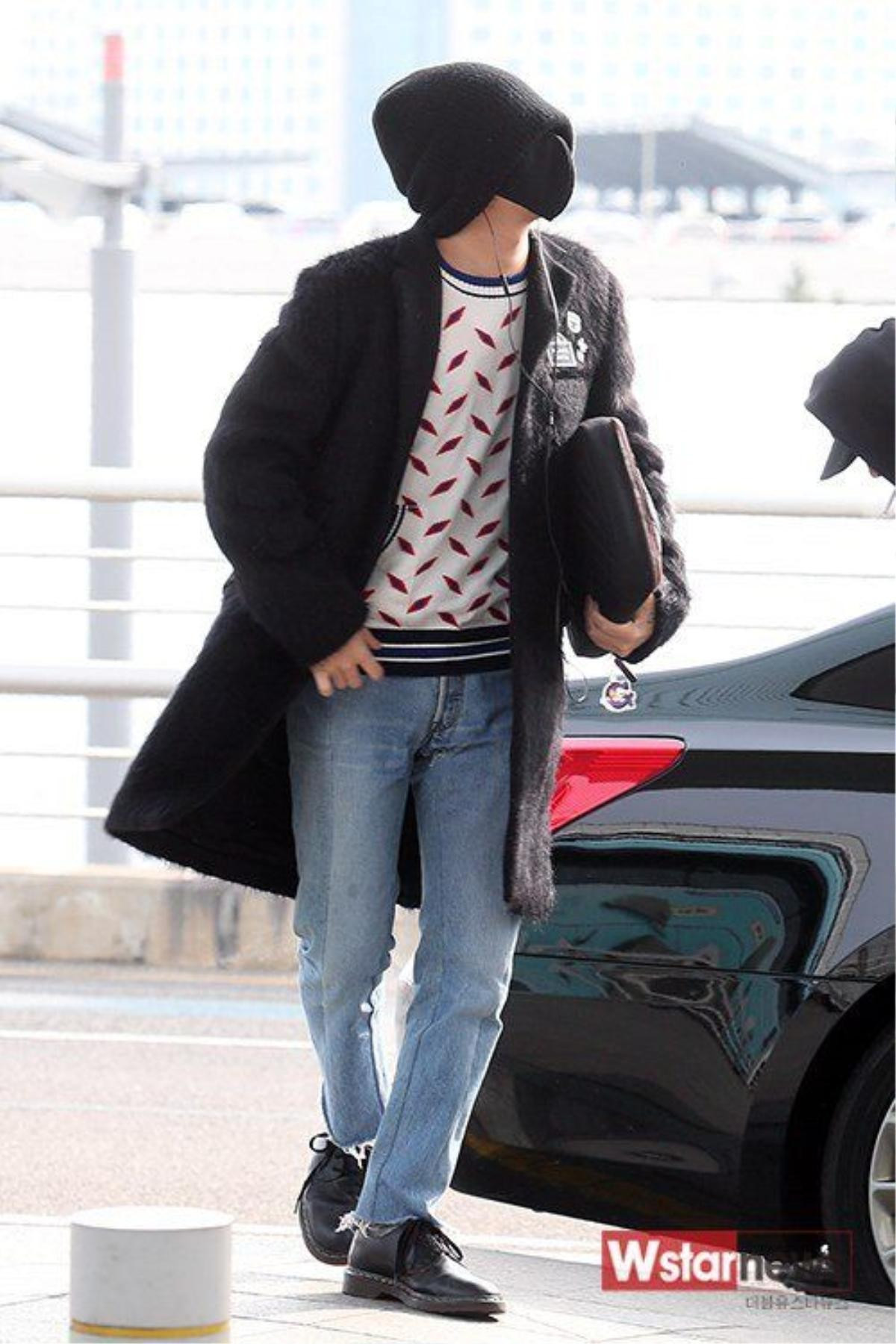 Trong khi đó, G-Dragon diện jeans, áo họa tiết và trechcoat. Trưởng nhóm Big Bang giữ thói quen giấu mặt mỗi khi ra sân bay bằng cách đội mũ len lùm xùm, đeo khẩu trang kín mít. 