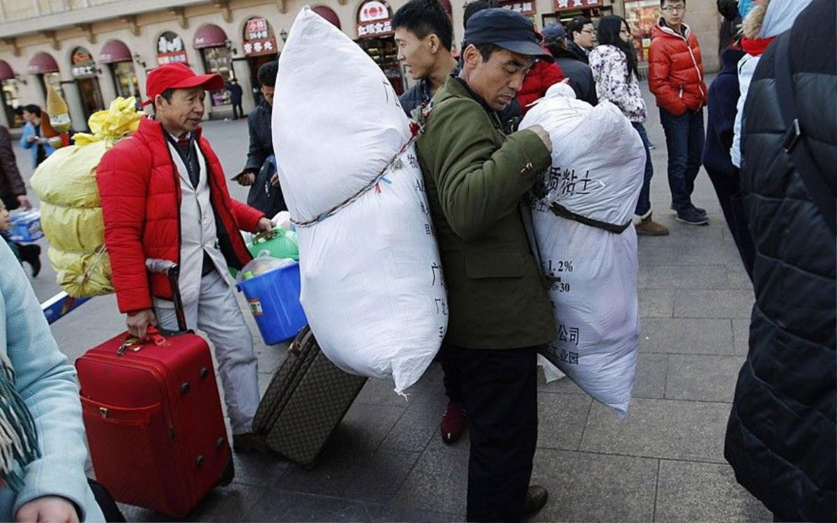 A man carries sacks as he stand in a line to enter a platform at a railway station in Beijing February 16, 2015. Chinese Ministry of Transport said a total of 2.807 billion trips are expected to be made during the 40-day Spring Festival travel rush, which started on February 4 and will last until March 16, Xinhua News Agency reported. REUTERS/Kim Kyung-Hoon (CHINA - Tags: TRANSPORT SOCIETY)