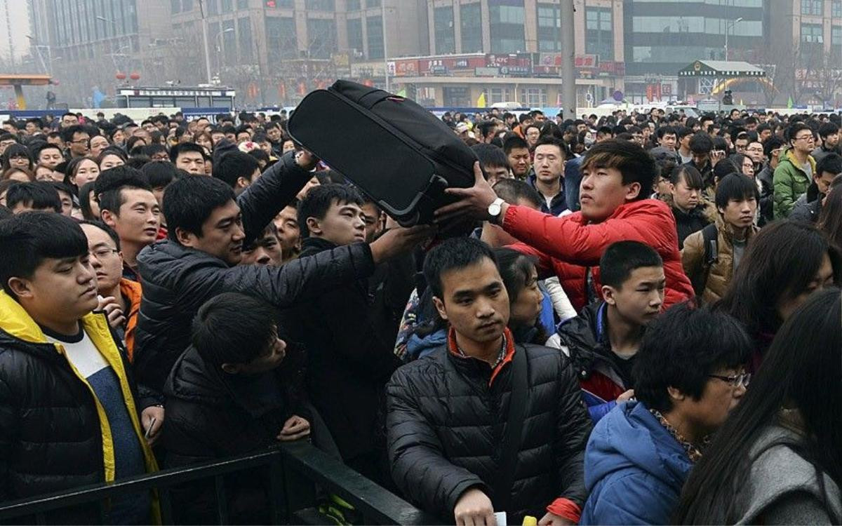 People pass a suitcase as they line up to enter a railway station in Beijing, February 15, 2015. Chinese Ministry of Transport said a total of 2.807 billion trips are expected to be made during the 40-day Spring Festival travel rush, which started on February 4 and will last until March 16, Xinhua News Agency reported. Picture taken February 15, 2015. REUTERS/Stringer (CHINA - Tags: SOCIETY TRANSPORT) CHINA OUT. NO COMMERCIAL OR EDITORIAL SALES IN CHINA