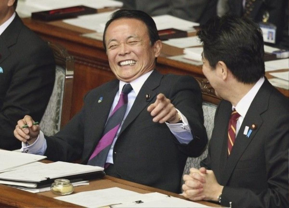 Japan's Finance Minister Taro Aso, left, has a light moment with Prime Minister Shinzo Abe during a plenary session at the lower house of parliament in Tokyo, Thursday, Feb. 28, 2013. Abe vowed to push ahead with more aggressive monetary easing with the nomination Thursday of Asian Development Bank President Haruhiko Kuroda to head Japanfs central bank. (AP Photo/Junji Kurokawa)