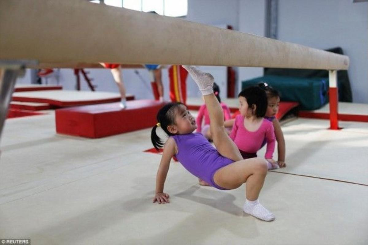 Một bé gái tập duỗi chân giữ thăng bằng trong lớp học Gym.