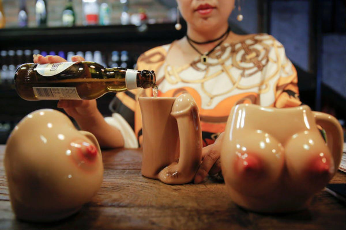 27-year-old Lu Lu, the owner of Ke'er restaurant (Shell in English), pours a drink into a penis-shaped cup at her restaurant in Beijing, China, May 26, 2016. With drinks served in breast-shaped cups and beers opened with bottle openers shaped like a wooden penis, the father and daughter team behind a Beijing S&M restaurant are encouraging customers to mix food with sex. Owner Lu Lu said business has been good since opening just under a year ago, with young Chinese streaming in to feast on seafood, such as lobster, under the gaze of mannequins wearing bondage gear. REUTERS/Kim Kyung-Hoon TEMPLATE OUT SEARCH "BEIJING SHELL" FOR THIS STORY. SEARCH "THE WIDER IMAGE" FOR ALL STORIES.