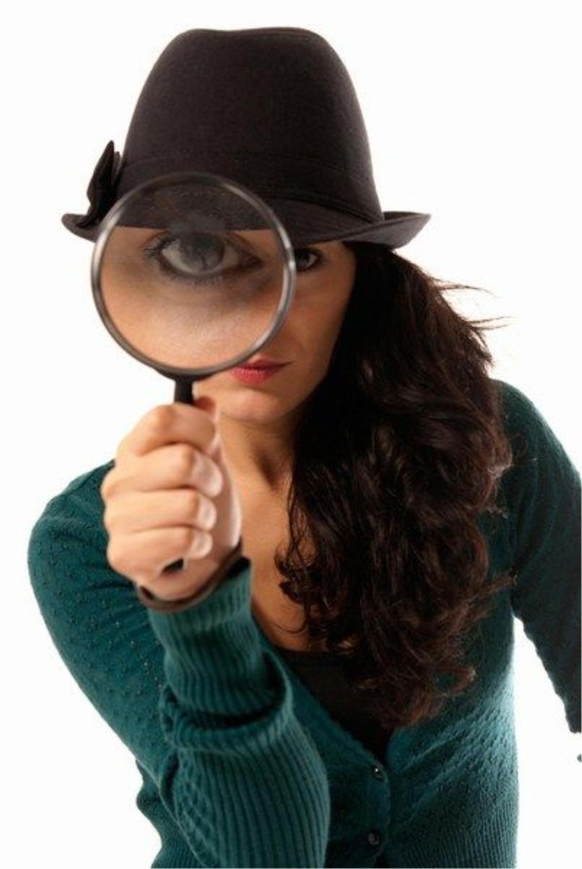 Young woman looking through magnifying glass loupe detective isolated on white background