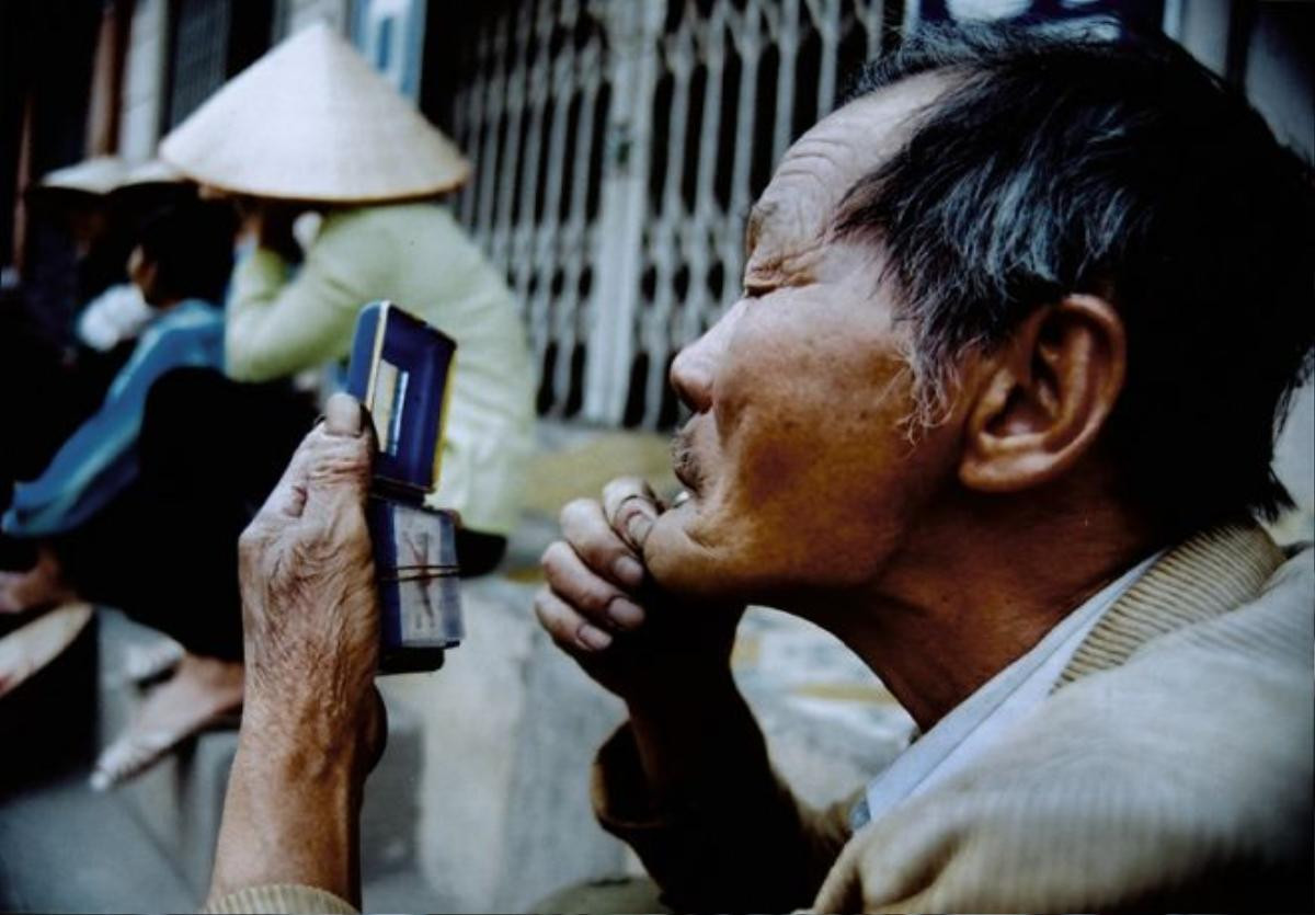 Cụ ông tranh thủ lúc rảnh rỗi nhổ râu, kiểm tra lại "dung nhan" trên hè phố Thủ đô.