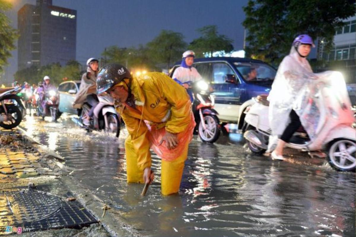 Nhân viên thoát nước cố gắng nhặt những mẩu vụn bị trôi vào chỗ khe nắp cống để nước rút nhanh hơn.