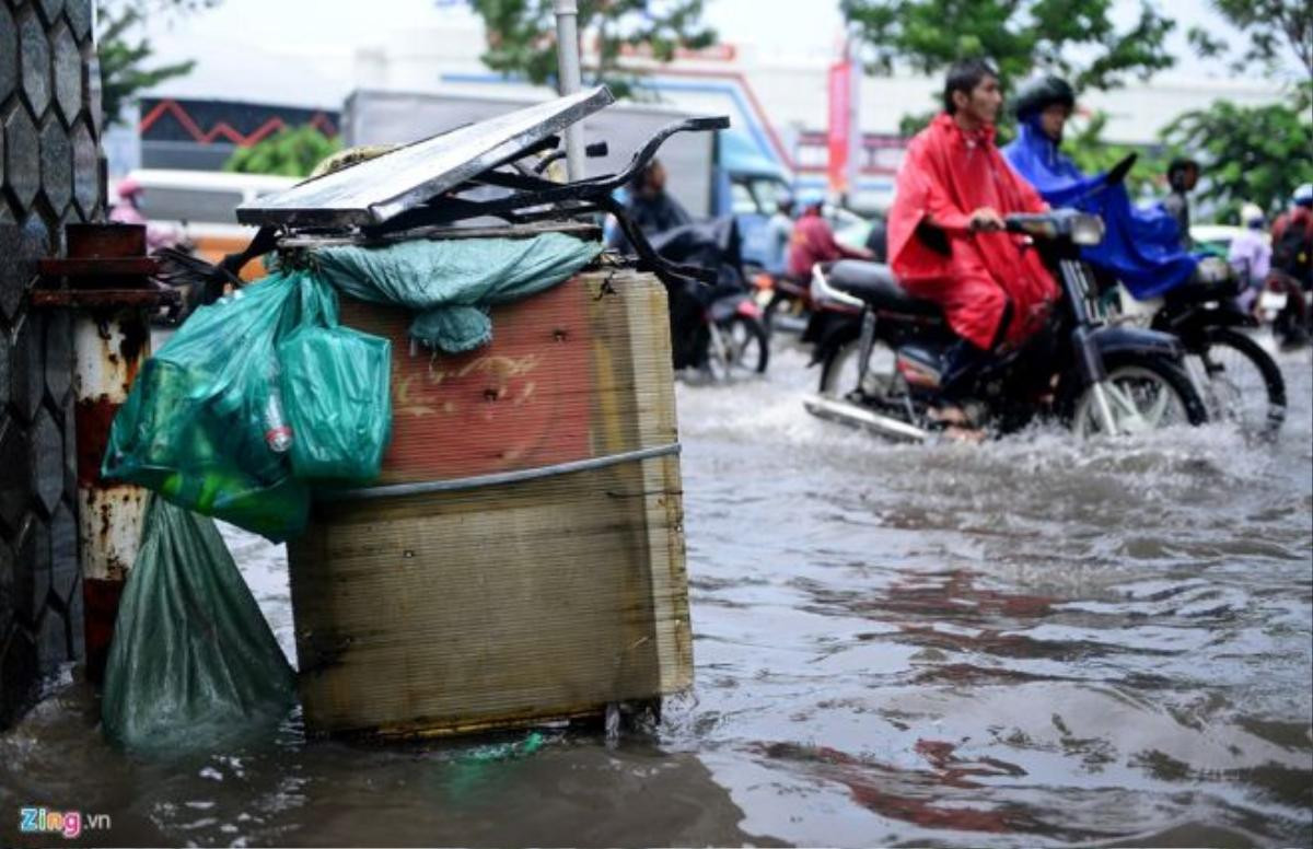 Đồ đạc của người bán hàng rong đầu đường Tiền Giang, đoạn giao với Trường Sơn bị ngâm trong nước. Nhiều người vội vàng vượt qua đoạn đường ngập nước để kịp vào sân bay.