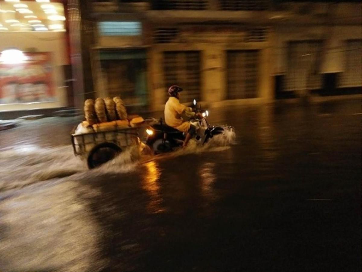 Nhiều người vất vả di chuyển trong nước ngập giữa khuya ở thành phố. Ảnh: Tùng Tin.