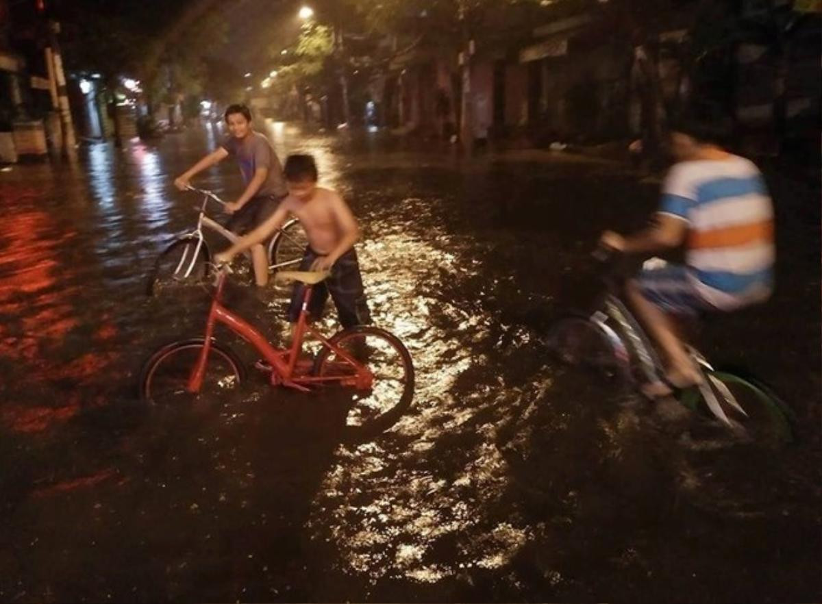 Một số trẻ em trên đường Mai Xuân Thưởng (quận 5) đùa nghịch trong nước ngập. Ảnh: Tùng Tin.