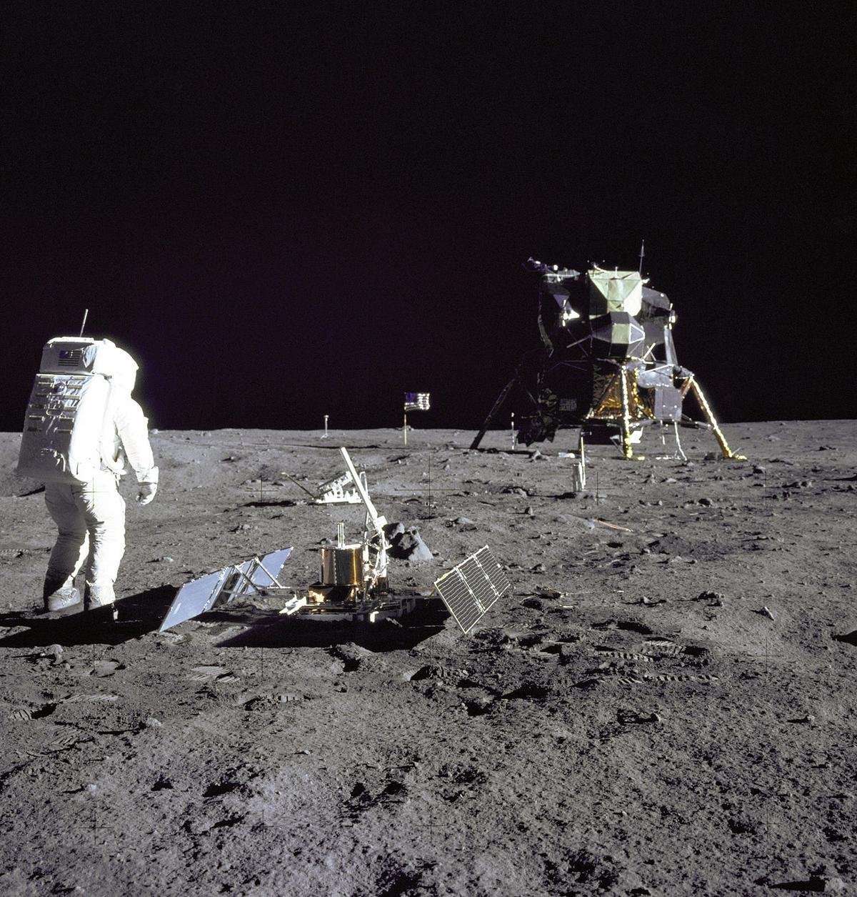 Buzz Aldrin đang thực hiện các thí nghiệm khoa học trên Mặt Trăng, ngay bên cạnh ông là bộ dụng cụ đo chấn động và xa hơn là thiết bị phản xạ laser.