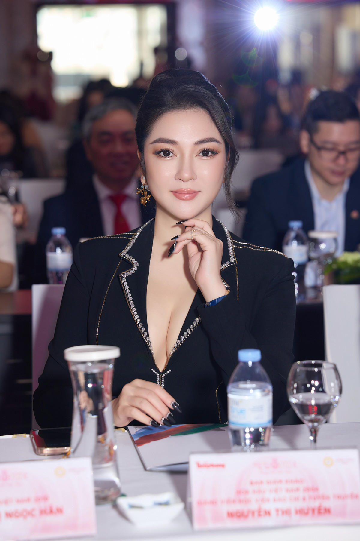 Chiếc áo vest chiết eo tinh tế, được đính kết tỉ mỉ với những đường viền đá lấp lánh, giúp tôn lên đường cong mềm mại của cô. Phần cổ áo khoét sâu vừa đủ để tạo điểm nhấn gợi cảm, nhưng vẫn giữ được sự trang nhã, đúng với phong cách quý phái của người đẹp khi ngồi ghế giám khảo cuộc thi.