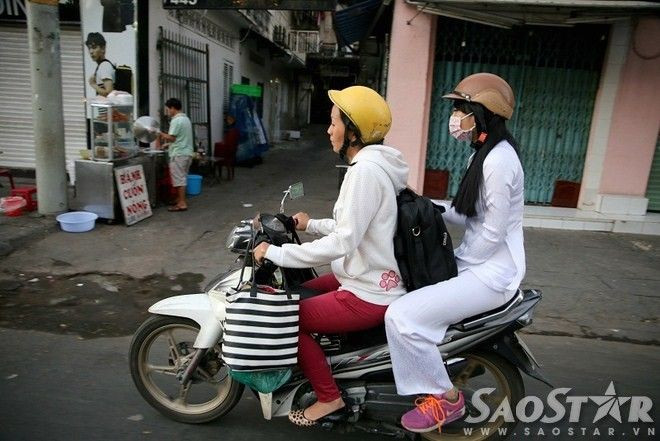 Cô nữ sinh được mẹ chở đi làm chủ quan không khoác thêm áo, phải giấu tay vào giữa hai chân cho bớt run.