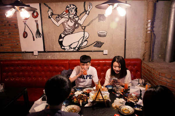 Customers eat a meal at Ke'er restaurant (Shell in English) in Beijing, China, May 26, 2016. With drinks served in breast-shaped cups and beers opened with bottle openers shaped like a wooden penis, the father and daughter team behind a Beijing S&M restaurant are encouraging customers to mix food with sex. Owner Lu Lu said business has been good since opening just under a year ago, with young Chinese streaming in to feast on seafood, such as lobster, under the gaze of mannequins wearing bondage gear. REUTERS/Kim Kyung-Hoon SEARCH "BEIJING SHELL" FOR THIS STORY. SEARCH "THE WIDER IMAGE" FOR ALL STORIES. EDITORIAL USE ONLY. NO RESALES. NO ARCHIVE.