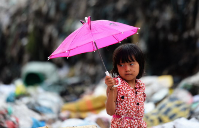 Cây dù nhặt được từ bãi rác là phương tiện để bé Trân che nắng che mưa.