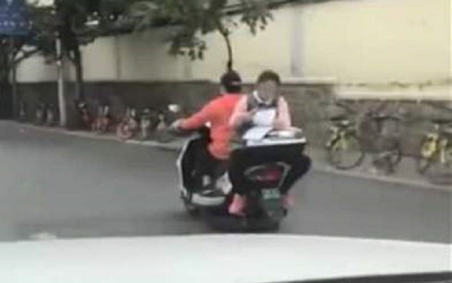 Choáng váng trước cảnh bé gái tranh thủ làm bài khi ngồi sau xe máy đang chạy Ảnh 2