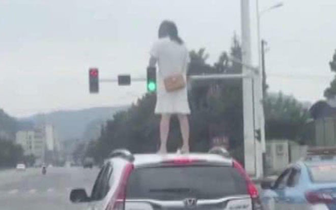 Cãi nhau với chồng, người phụ nữ nhảy lên nóc xe ô tô đứng Ảnh 2