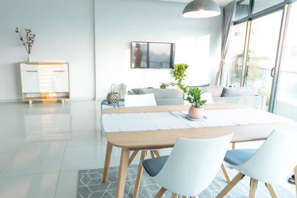 Phòng khách được đóng khung bởi ghế sofa màu xám sáng, bàn trà gỗ nhỏ xinh và thảm trải sàn họa tiết kẻ ca rô trẻ trung.