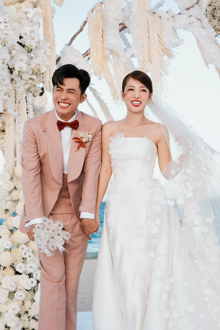 Trong đám cưới, chú rể Gin Tuấn Kiệt diện vest hồng, đeo nơ đỏ. Còn cô dâu Puka lựa chọn thiết kế váy cưới màu trắng, khéo khoe bờ vai trần đầy quyến rũ. 