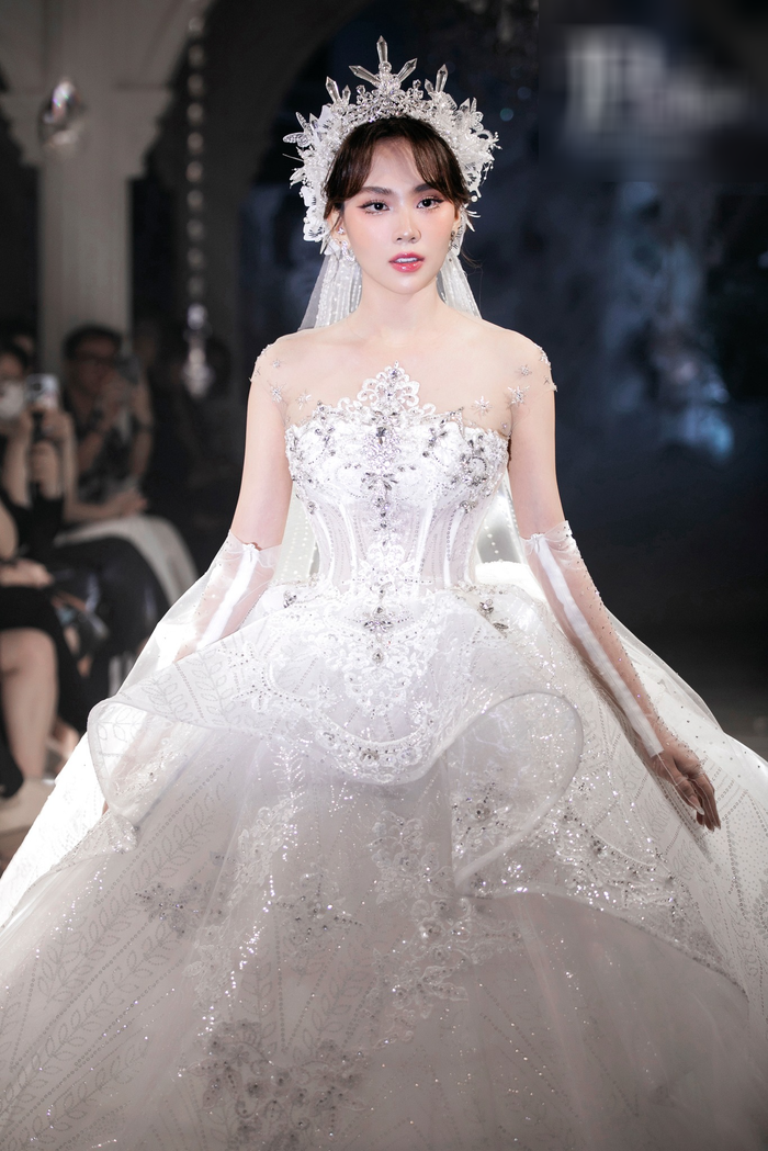 Hoa hậu Mai Phương trình diễn vedette cùng chiếc ballgown giật tầng bồng bềnh. Cô sải bước với thần thái, kỹ năng catwalk chuyên nghiệp khiến khán giả khó rời mắt. Người đẹp đã thể hiện thành công phần trình diễn của mình với chiếc váy dài 3.5m và nặng 12kg.&nbsp;