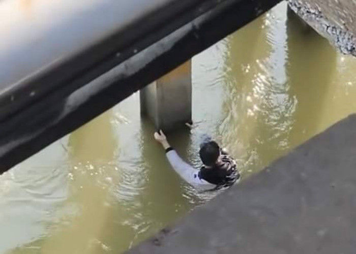 Nam thanh niên cố bám đu vào cầu chờ lực lượng chức năng đến giải cứu. (Ảnh: ANTĐ).