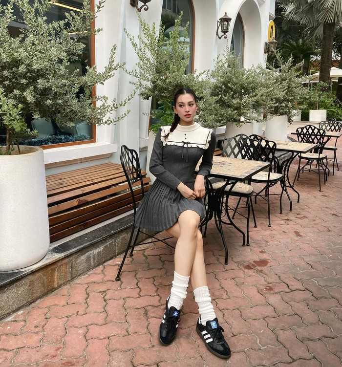 Checkin tại không gian mang hơi hướm cổ điển, Trần Tiểu Vy hóa thân thành tiểu thư điệu đà với bộ váy cách điệu nhuộm tông xám. Phần cổ áo yếm điểm xuyết viền bèo nhún, thắt nơ cùng thiết kế xếp ly chân váy giúp nàng hậu thêm phần dịu dàng khi lên hình. Ở layout này, Tiểu Vy lựa chọn kiểu tóc tết với phần mái rẽ ngôi giữa, tôn lên tỉ lệ gương mặt và đường nét thanh tú.  