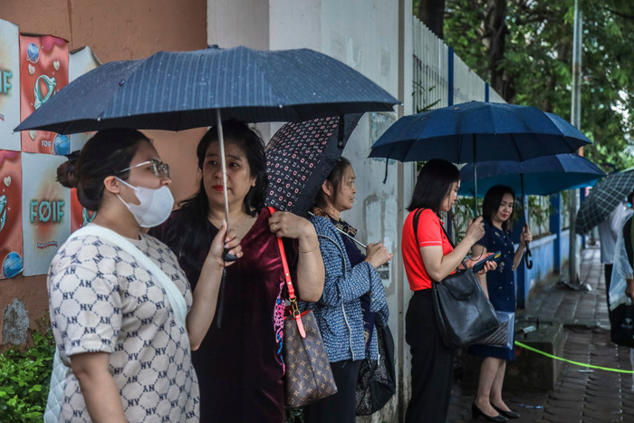 Bất chấp thời tiết mưa gió, nhiều phụ huynh vẫn nán lại cổng trường sau khi đưa con vào phòng thi