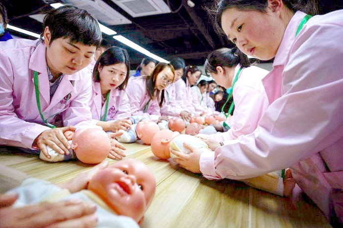 Học viên đang thực hành chăm sóc trẻ sơ sinh tại các lớp kỹ năng bảo mẫu ở Thượng Hải (Trung Quốc) - Ảnh: Reuters