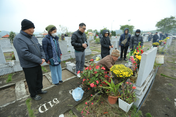 Ông Nguyên đang làm lễ tạ mộ mời vợ đã khuất cùng tổ tiên về đón Tết, xung quanh có các con cháu của ông