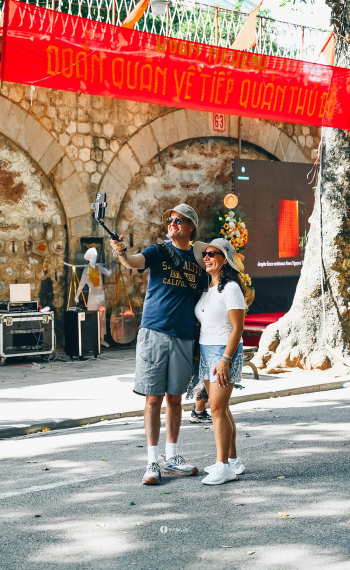 Du khách nước ngoài chụp ảnh kỷ niệm tại phố bích hoạ Phùng Hưng. Ảnh: Vương Lộc