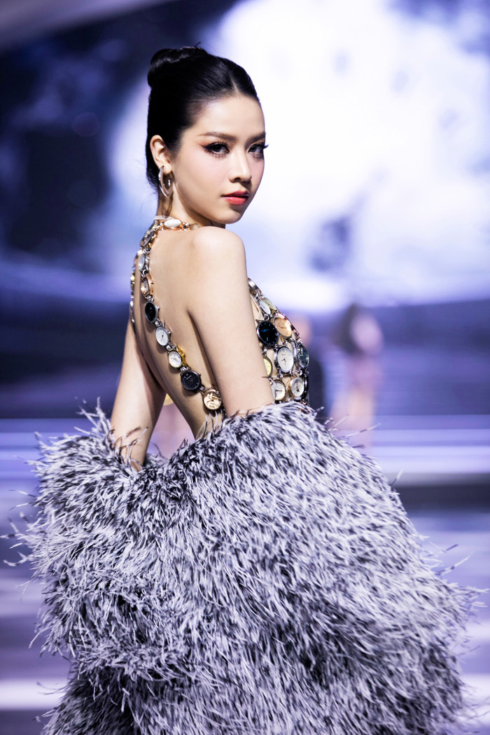 Hoa hậu Thanh Thủy đảm nhận vị trí first face. Cô diện chiếc đầm ngắn được đính kết hoạ tiết đồng hồ cực kỳ thú vị - biểu tượng cho hình ảnh thời gian hối hả, dồn dập. 
