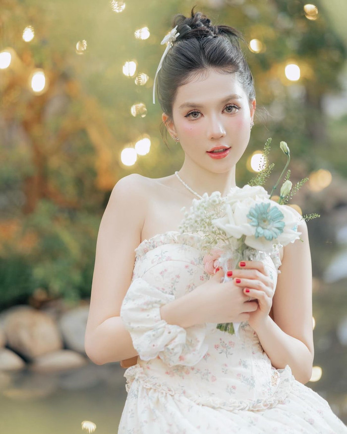 Mới đây, Ngọc Trinh gây ngỡ ngàng với bộ ảnh lấy cảm hứng từ trang phục cô dâu đầy quyến rũ và tinh tế. Diện 'chiếc váy cưới đặc biệt', Ngọc Trinh mang đến một hình ảnh kết hợp hoàn hảo giữa nét ngây thơ và sang trọng, nhưng vẫn toát lên vẻ đẹp thuần khiết và lôi cuốn. Đặc biệt khi cầm trên tay bó hoa nhỏ nhắn, Ngọc Trinh tạo nên vẻ đẹp nhẹ nhàng và đầy tinh tế.