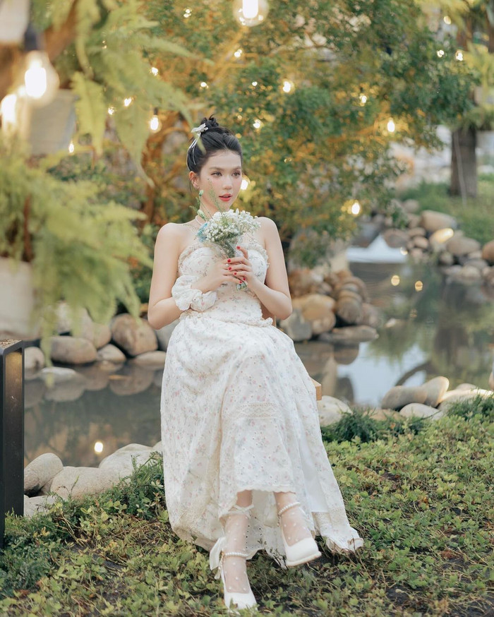 'Chiếc váy cưới' mà Ngọc Trinh lựa chọn có thiết kế độc đáo, khác biệt với chất liệu vải mềm mại cùng những họa tiết hoa nhỏ, mang lại cảm giác lãng mạn và bay bổng. Phần thân váy ôm nhẹ, giúp tôn lên vóc dáng mảnh mai của người đẹp gốc Trà Vinh.
