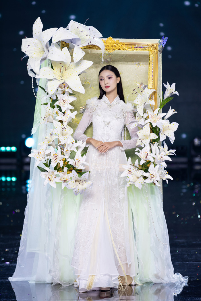 Thí sinh Nguyễn Thị Cẩm Ly, đến từ Đắk Lắk được khen ngợi nhan sắc ngọt ngào cùng thiết kế 'Thiếu Nữ Bên Hoa'. Bộ trang phục được lấy cảm hứng từ bức tranh “Thiếu nữ bên hoa huệ”- một tác phẩm tranh sơn dầu do họa sĩ Tô Ngọc Vân sáng tác năm 1943. Thiết kế mô tả bức tranh chân dung của thiếu nữ mặc áo dài trắng bên cạnh lọ hoa huệ trắng. Những đường cong, nếp gấp trên tà áo dài hòa quyện vào nhau tạo thành màu sắc nhẹ nhàng, nhấn mạnh vẻ đẹp thanh tao của người con gái Hà Nội. 