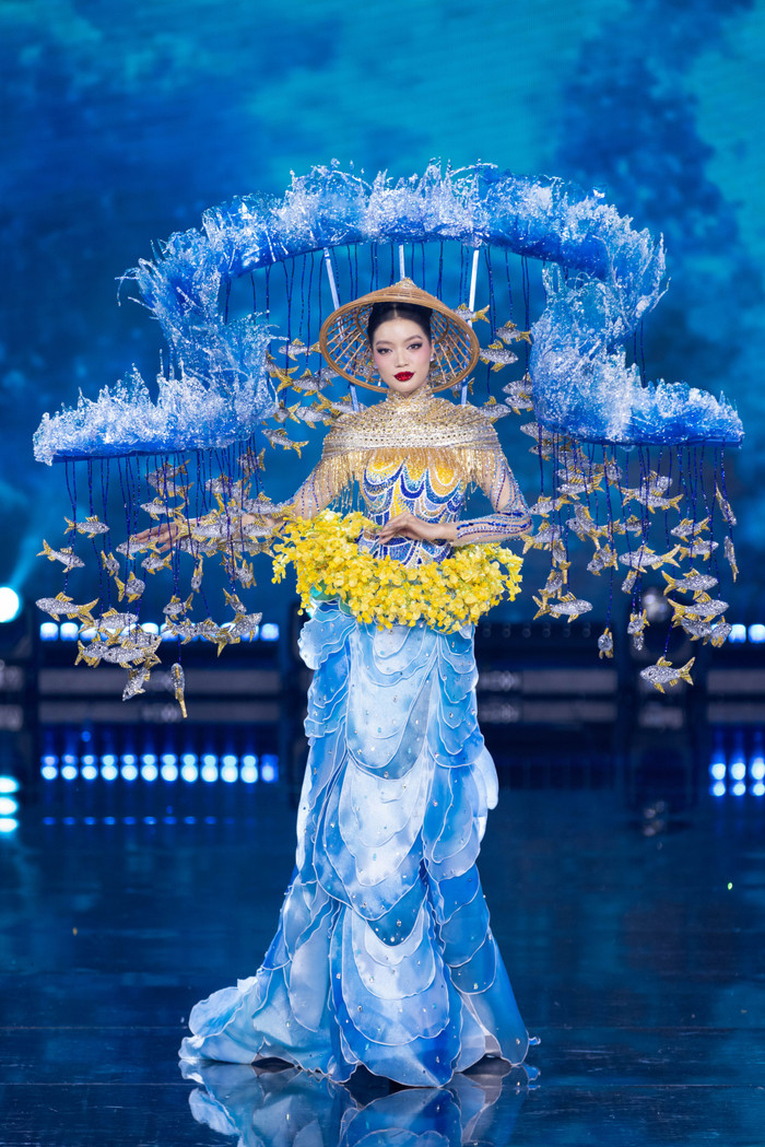 Á hậu 3 Miss Grand Vietnam 2024 - Lâm Thị Bích Tuyền trình diễn mãn nhãn trong thiết kế 'Tinh Túy Mùa Nước Lên'. Bộ trang phục được lấy cảm hứng từ mùa nước nổi của đồng bằng sông Cửu Long được bồi đắp bởi phù sa. Hằng năm mỗi độ tháng 7 đến tháng 10 Âm lịch, con nước từ thượng nguồn sông MeKong đổ về đồng bằng sông Cửu Long, phù sa theo con nước mang lại sự dồi dào trù phú cho cho vùng đất này, trong đó có những sản vật đặc trưng mà dân dã: như là cá linh, bông điên điển,…