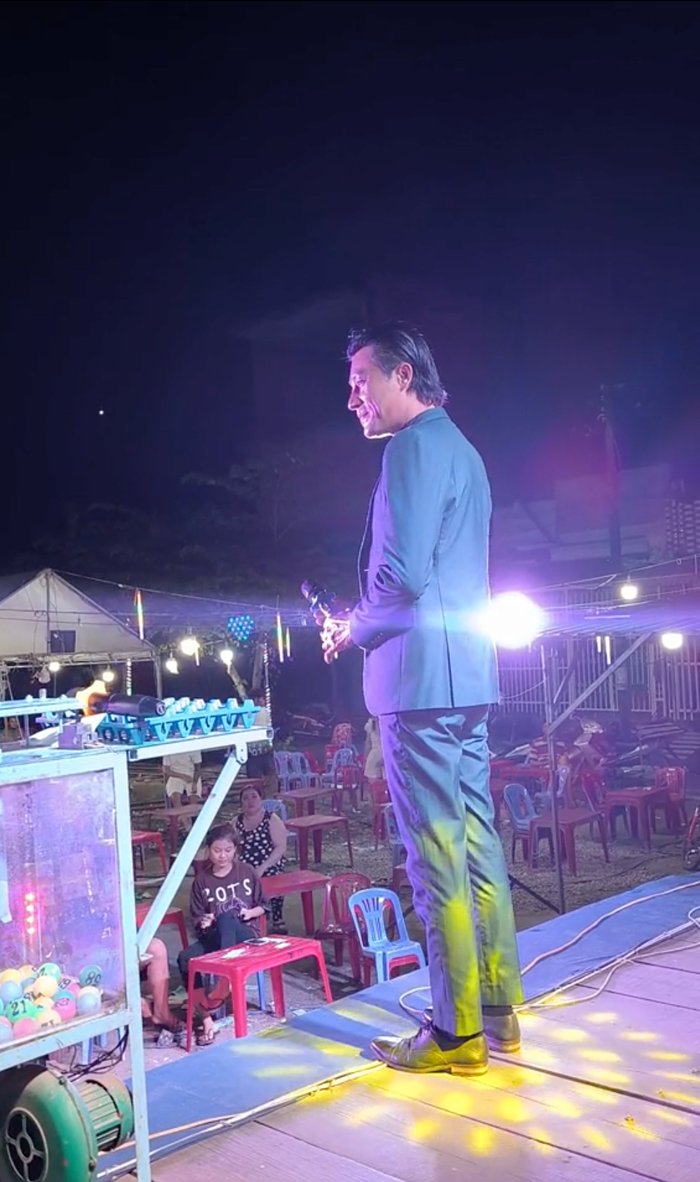 Hình ảnh diễn viên Đông Dương hát tại một sân khấu hội chợ.