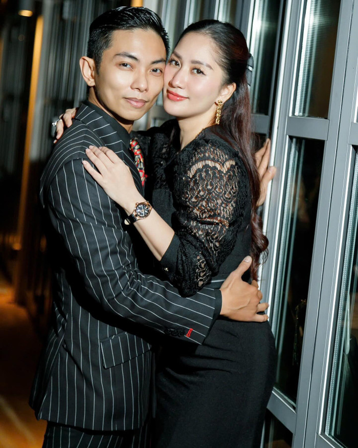 Khánh Thi chọn diện kiểu đầm kín đáo màu đen được may bằng chất vải ren. Điểm đáng khen trên diện mạo của người đẹp chính là tông trang điểm 'hack tuổi'. Nhờ gương mặt vốn có độ sắc sảo, Khánh Thi chỉ cần 'họa mặt' nhẹ nhàng cũng đủ tôn được nhan sắc. Ngoài ra, làn da căng bóng cũng giúp cô nàng trở nên trẻ trung hơn rõ khi 'mặt kề mặt' với Phan Hiển. 