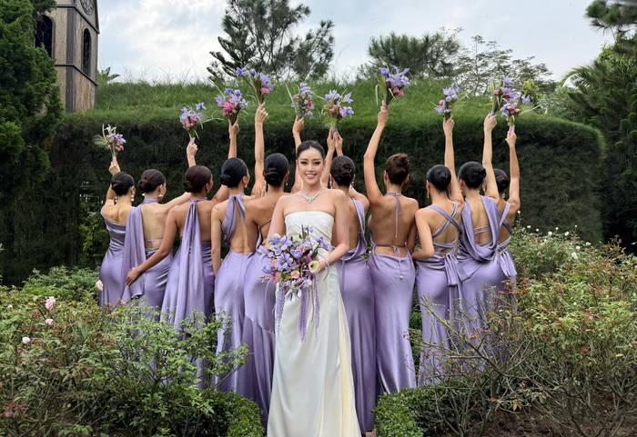 Trước đó, Khánh Vân từng hé lộ 'teaser' những thước ảnh cưới bên 10 nàng hậu phù dâu. Trang phục cô dâu của cựu Hoa hậu Hoàn vũ Việt Nam ưu tiên phom dáng đơn giản đường cắt may thanh lịch, cổ điển. Riêng các nàng phù dâu cũng được chọn váy áo tôn được vóc dáng cơ thể. 