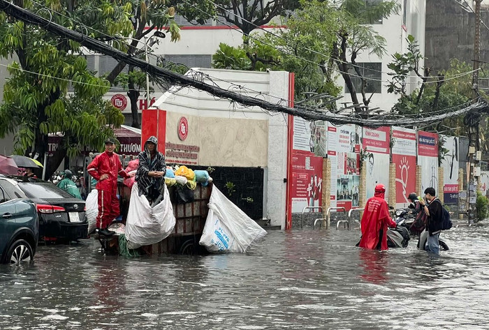 Nhân viên gom rác bất lực không thể tiếp tục công việc phải 'đứng hình giữa biển nước' rút chậm trên đường D5, Q.Bình Thạnh, lúc 16 giờ - Ảnh: Thanh niên
