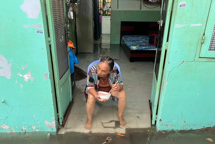 Bà Liên, hẻm 432 đường Xô Viết Nghệ Tĩnh cho biết: 'Mưa lớn nước ngập vào nhà tôi hoài. Dọn dẹp mệt đói quá, tôi ăn cơm chờ nước rút dọn tiếp' -  Ảnh: Thanh niên