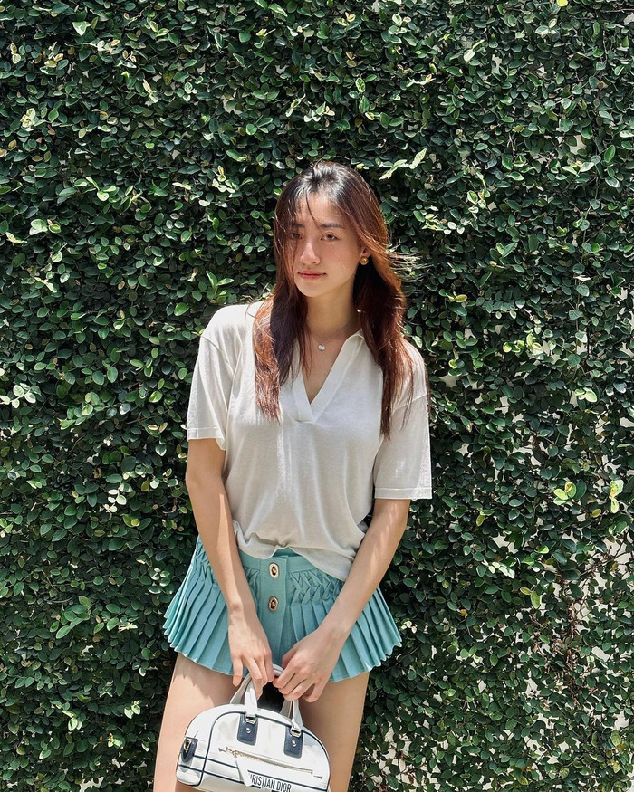 Hoa hậu Lương Thùy Linh thu hút với vẻ ngoài đơn giản nhưng vô cùng thanh lịch khi kết hợp áo thun trắng và chân váy ngắn xếp ly xanh pastel. Đặc biệt, bộ trang phục giúp cô khoe trọn đôi chân dài thon gọn và nuột nà, một trong những điểm nổi bật của Lương Thùy Linh.