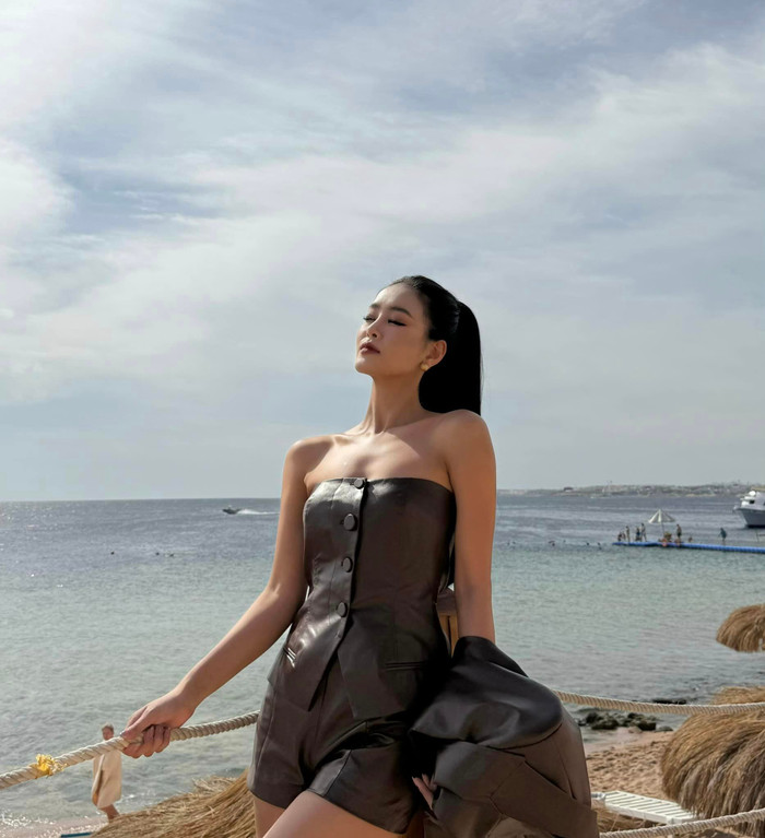 Tham gia một sự kiện tại bãi biển, Bùi Khánh Linh chứng tỏ bản lĩnh thời trang đẳng cấp của mình. Diện trên người set đồ màu nâu đơn giản nhưng vẫn toát ra sự cá tính, thời thượng. Chất liệu phi bóng 'kén người mặc' nhưng cũng không làm khó được đại diện Việt Nam. Cô còn khéo léo mix cùng chiếc áo khoác kiểu dáng cape để khiến visual của mình trở nên sang trọng hơn. 