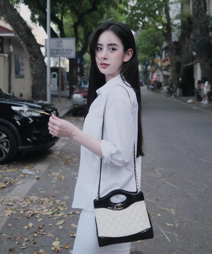 Dạo chơi phố xá, Hương Liên 'lên' cây đồ trắng đơn giản, thoải mái. Để tăng thêm phần sang chảnh, bạn gái Tuấn Ngọc phối cùng phụ kiện túi xách đến từ 'nhà mốt' có Jennie (BLACKPINK) làm đại sứ toàn cầu. Thiết kế này mang form dáng hình vuông, phối giữa hai mảng màu đối lập đen - trắng và được bán với mức giá khoảng 130 triệu đồng.