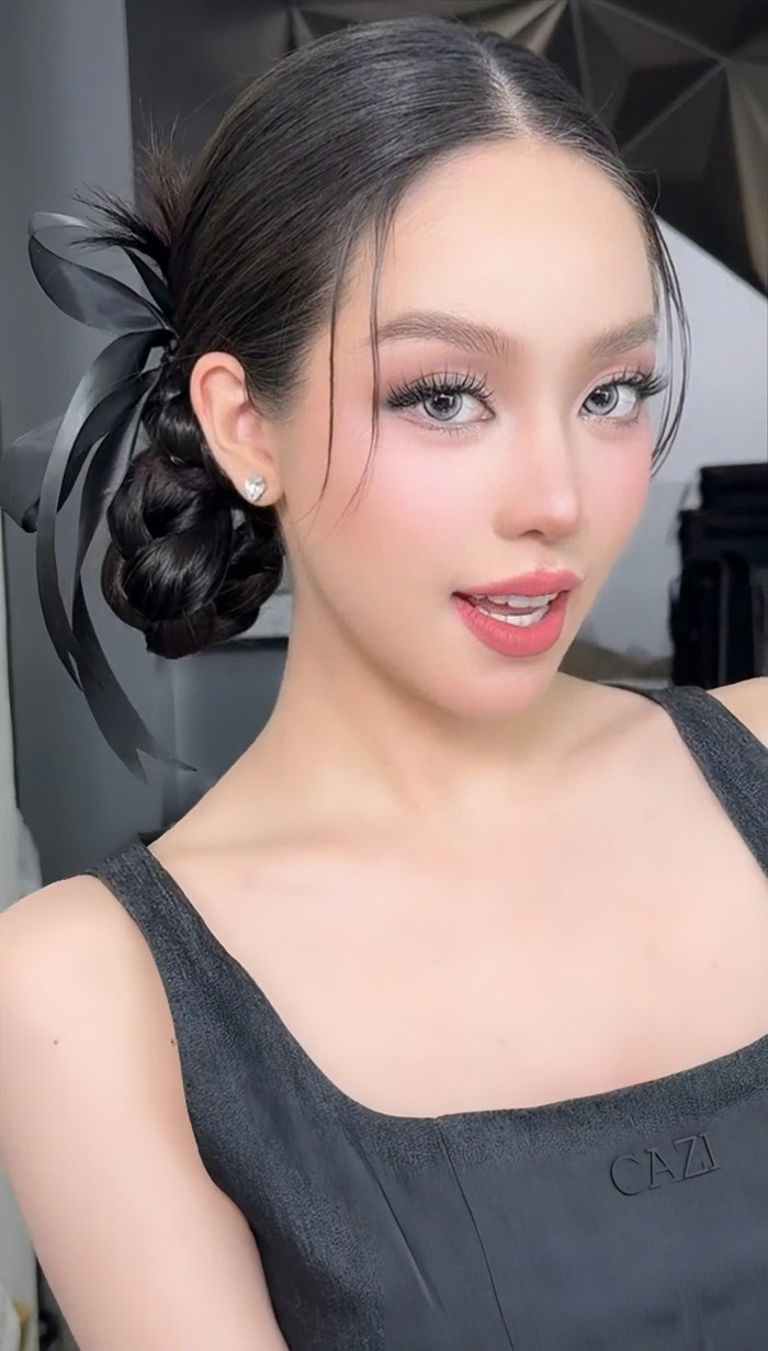 Thanh Thủy gây ấn tượng khi sử dụng kính áp tròng tông xanh biển kết hợp hàng mi cong vút và kiểu đánh khối tạo cằm V-line. Kiểu tóc tết hai bên thịnh hành kết hợp  ruy băng thắt nơ đen dáng mảnh được nàng hậu yêu thích thực hiện cho tạo hình lần này. Ở góc quay cận, ngũ quan hài hòa của Hoa hậu Thanh Thủy được phô bày trọn vẹn.  