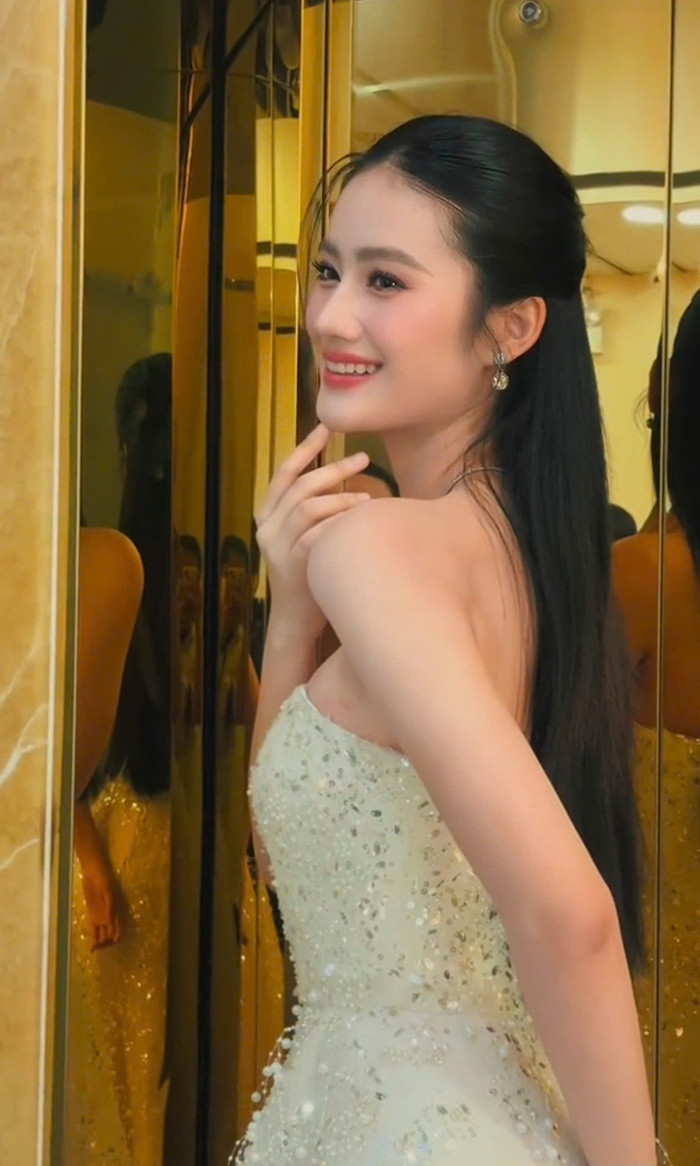 Trong đoạn clip đăng tải, Hoa hậu Ý Nhi khoe vóc dáng với mẫu váy dạ hội cúp cung điểm xuyết nhũ bạc lấp lánh. Thiết kế tinh giản phần tay giúp người mặc khoe trọn đôi vai trần trắng mịn. Tô điểm cho khu vực xương quai xanh, nàng hậu phối cùng kiểu dây chuyền bạch kim có mặt đá thả rũ.  